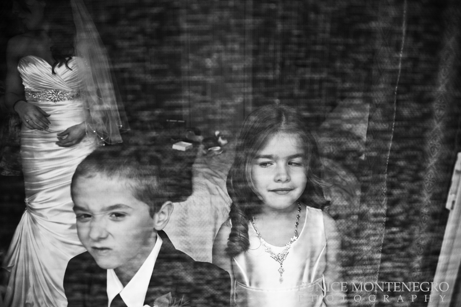 BW awarded wedding picture of a flower girl, ring bearer and bride getting ready behind a screen door