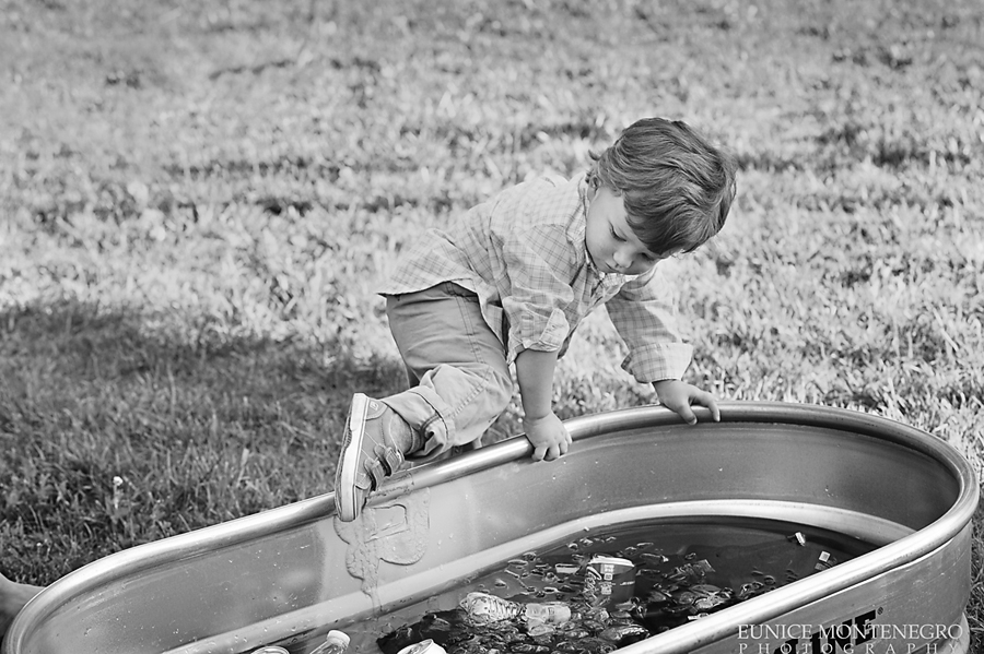 black and white picture of a kid trying to jump in a cooler during a wedding reception.