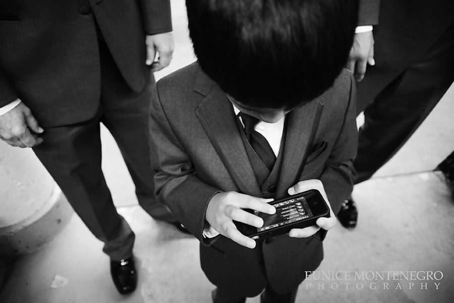 Black and white photograph of ring bearer playing on a divice 