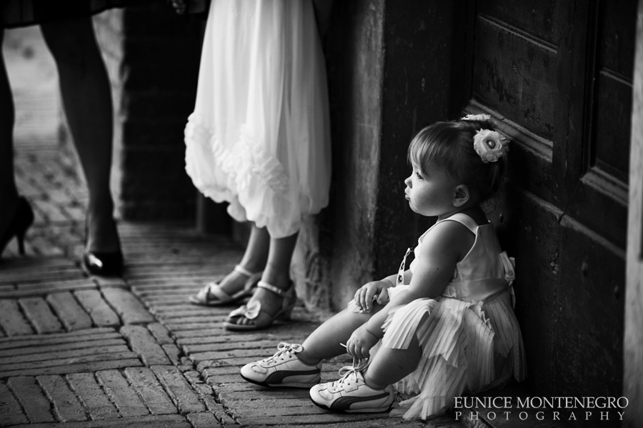 bw photo of a flower girl in a wedding touching her shoes